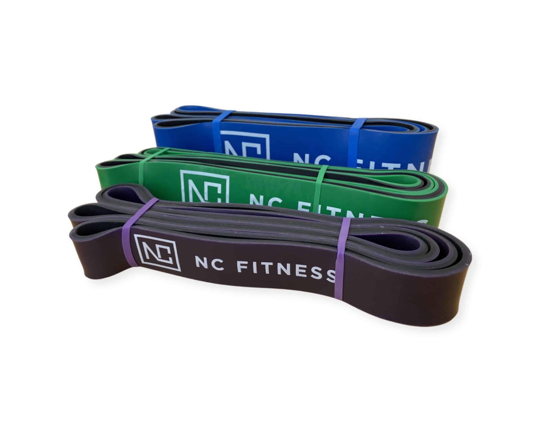 Three NC Fitness resistance bands in blue, green, and purple stacked together.