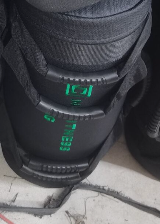 Black NC Fitness weight plate with green logo lettering.