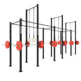 Commercial gym squat racks with red weight plates and gymnastic rings.